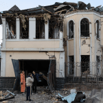 Cold Ukrainians in front of a house destroyed during the war with Russia.