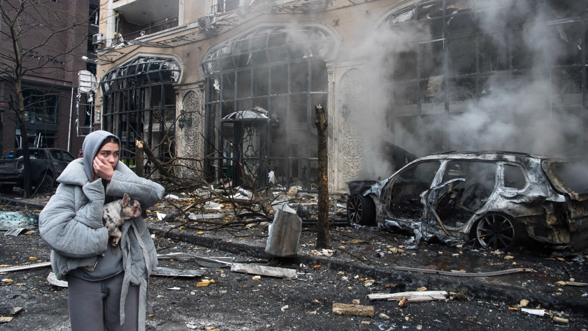 A woman and her dog walk on street in Kyiv after a Russian missile has destroyed the center of the city.